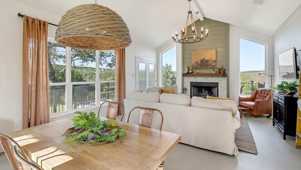 Amplia sala de estar con chimenea, comedor con mesa y sillas de madera, y un ventanal con vistas al exterior.