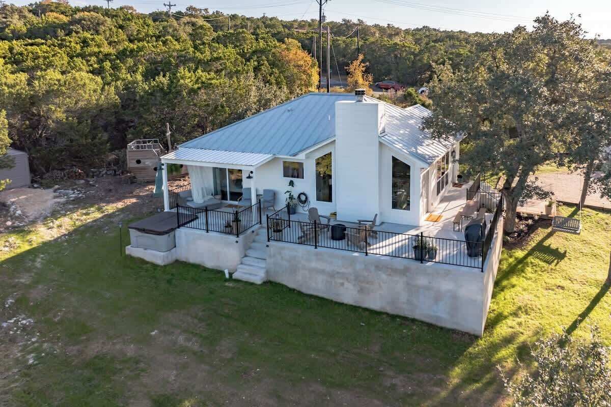 A modern house with a metal roof, a covered porch, and a fenced yard.