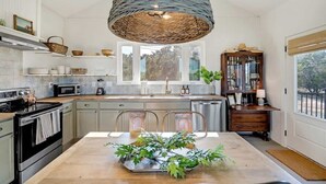 Una cocina moderna con una isla grande, electrodomésticos de acero inoxidable y una lámpara colgante de diseño con trenzado.