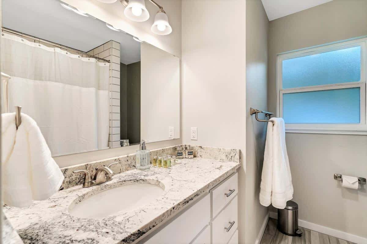 Une salle de bain avec un grand lavabo, un miroir, un porte-serviettes et une fenêtre.
