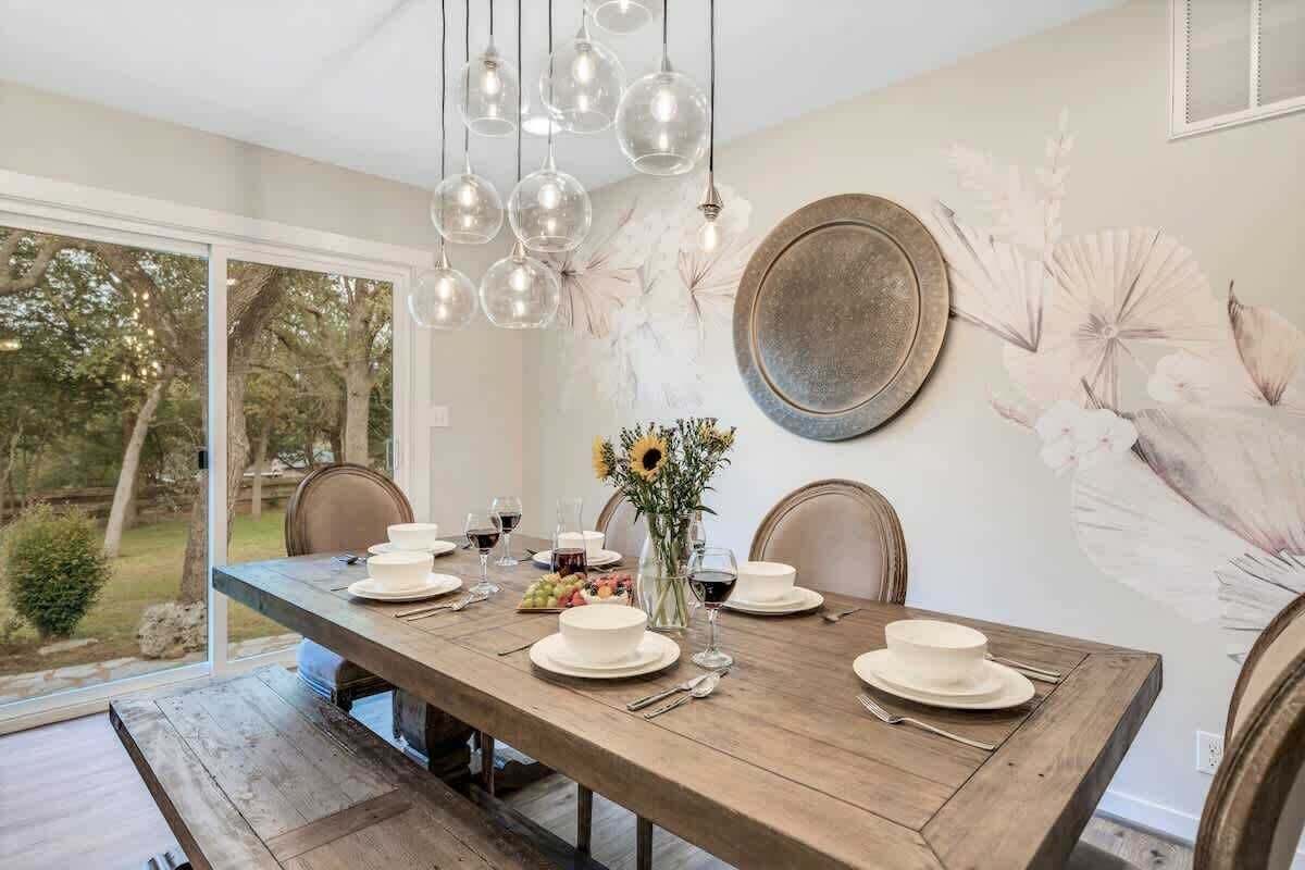 Un coin repas avec une table en bois, des assiettes blanches et un vase rempli de tournesols.