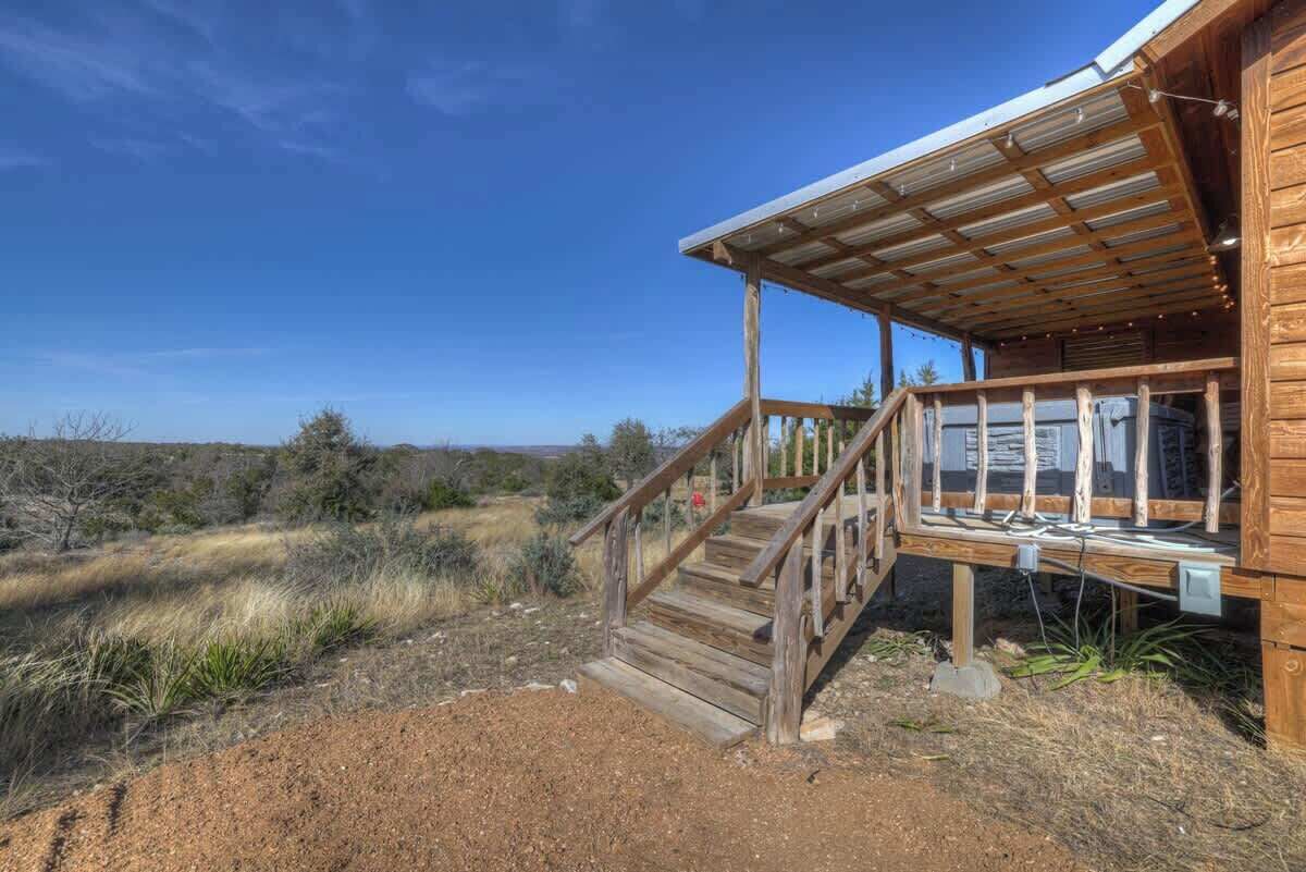 A wooden cabin with a wooden staircase leading to a covered porch.
