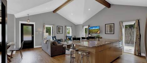 A spacious kitchen with a large island, wooden beams on the ceiling, and a dining area with a sofa and chairs.