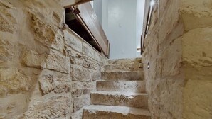 A narrow stone staircase leading upwards in a building with rough, textured walls.