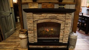 Una chimenea de piedra con fuego, una puerta de madera y decoración rústica.