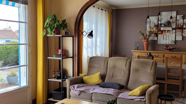 A cozy living room with a sofa, a wooden dining table, and a bookshelf. - A 5mn de la mer et du Bourg ,une Villa Plain Pied Vous Attend ! (Préfailles)
