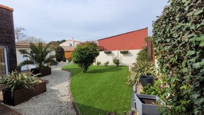 A modern house with a wooden deck, a small lawn, and various potted plants. - A 5mn de la mer et du Bourg ,une Villa Plain Pied Vous Attend ! (Préfailles)