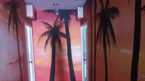 Un passadís amb un mural de palmeres i un atardec