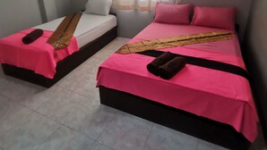Una habitació amb dos llits, cadascun amb un estovat rosa i una franja decorativa marró. Hi ha una finestra amb cortines transparents i una unitat de climatització a la paret.