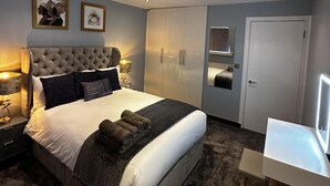 A modern bedroom with a large bed, a wardrobe, a desk, and two framed pictures on the wall. - Immaculate 1-bed Apartment in Chelsea London (London)
