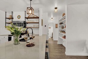 Une cuisine moderne avec des meubles blancs, un îlot central et un coin repas.