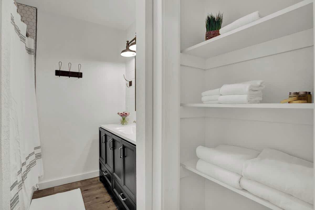 A modern bathroom with a white vanity, dark cabinets, and a towel rack.