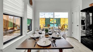 Un comedor con una mesa preparada para cuatro, ventanas amplias y vistas al exterior.