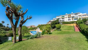 A residential area with a large tree, a swimming pool, and a multi-story building with balconies. - Sea Views 1 Bed Apt Colinas Del Faro (El Faro)