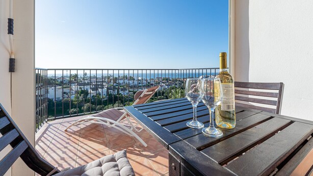 A balcony with a table set for two, featuring a bottle of wine and two glasses. - Sea Views 1 Bed Apt Colinas Del Faro (El Faro)