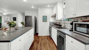 A modern kitchen with white cabinets, stainless steel appliances, and a wooden floor. - Gorgeous Bluebonnet House With Deck and Fire Pit (Fredericksburg)
