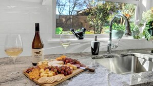 Una encimera de cocina con una tabla de quesos, una botella de vino y copas.