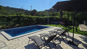 A swimming pool with lounge chairs and a pergola. - Apartment Dawn with playground and pool (Ostrvica- Omiš)
