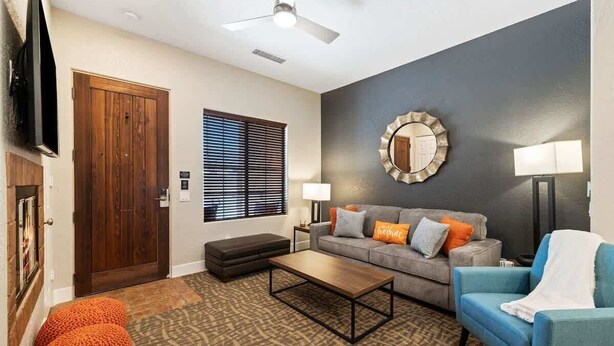 A living room with a sofa, ottoman, coffee table, and a television.