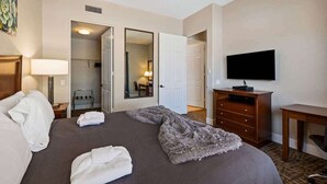 A hotel room with a bed, a TV, a dresser, and a mirror.