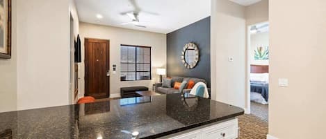 A modern kitchen with granite countertops, a built-in oven, and a dining area with a dark table and chairs.