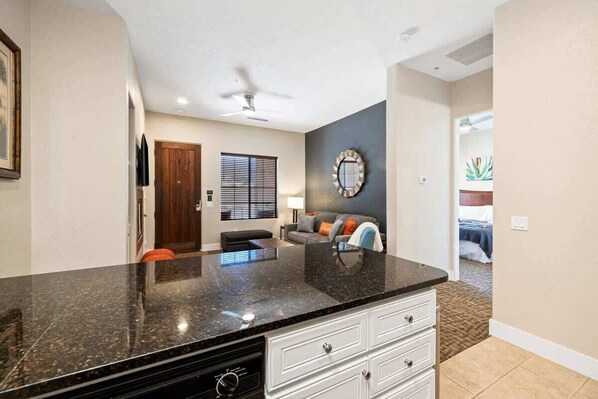 A modern kitchen with granite countertops, a built-in oven, and a dining area with a dark table and chairs.
