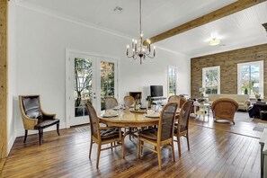 Een eetruimte met een houten tafel, zes stoelen en een kroonluchter.