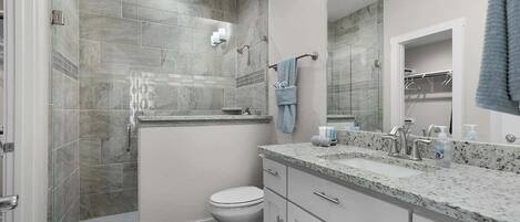Ein modernes Badezimmer mit Dusche, Toilette und Waschtisch mit Waschbecken und Spiegel.