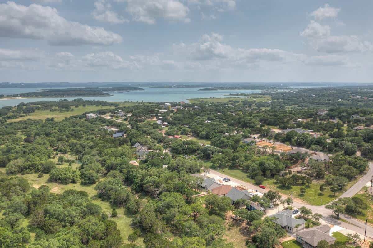 An aerial view of a residential area with houses, roads, and a large body of water in the background.