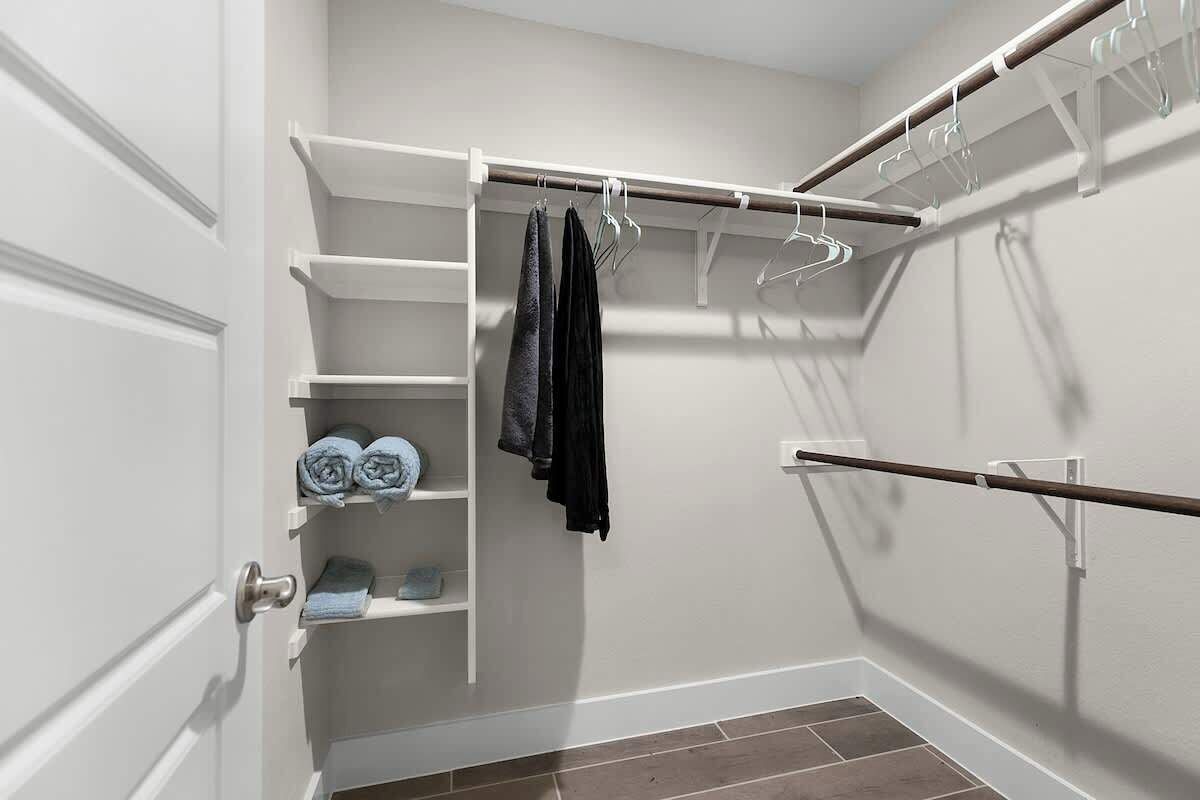 A walk-in closet with shelves, a hanging rod, and a door.