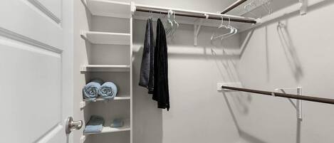 A walk-in closet with shelves, a hanging rod, and a door.