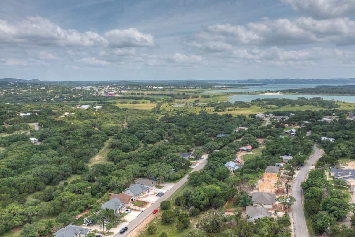 An aerial view of a residential area with houses, roads, and a large body of water in the distance.