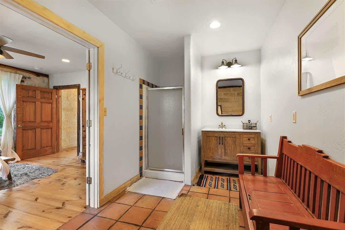 Un bagno con doccia, lavandino, specchio e mobili in legno.