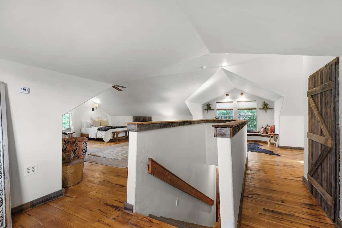 Un loft spacieux avec un plafond haut, un plancher en bois et un espace salon central comprenant un canapé et une table basse.