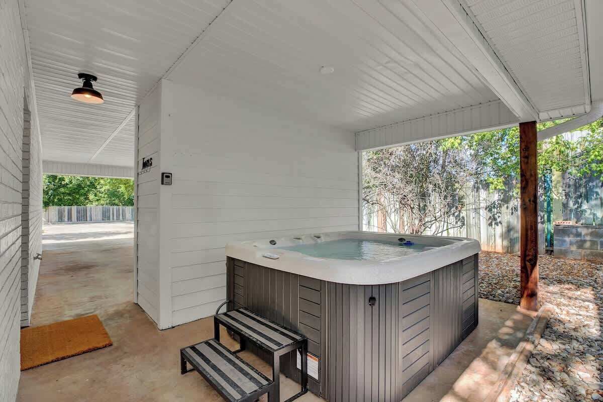 Un bain à remous situé dans un espace extérieur abrité, accessible par des marches.
