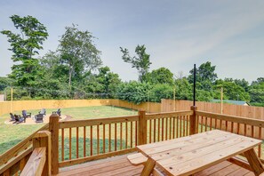 Eine Holzterrasse mit Picknicktisch und -stühlen, umgeben von einem Holzzaun und Bäumen.
