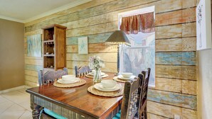 A wooden dining table with placemats, white plates, and a vase of flowers.