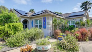 A house with solar panels, a sign reading 'Beach,' and various plants in the garden.