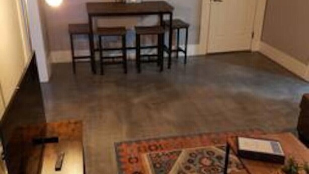 Una habitación con una mesa de comedor, sillas, un tapete y una lámpara.
