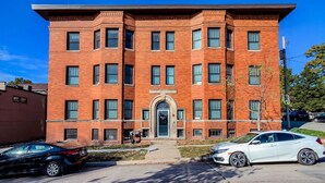 Un edificio de varios pisos de ladrillo con entrada central, ventanas amplias y techo plano.