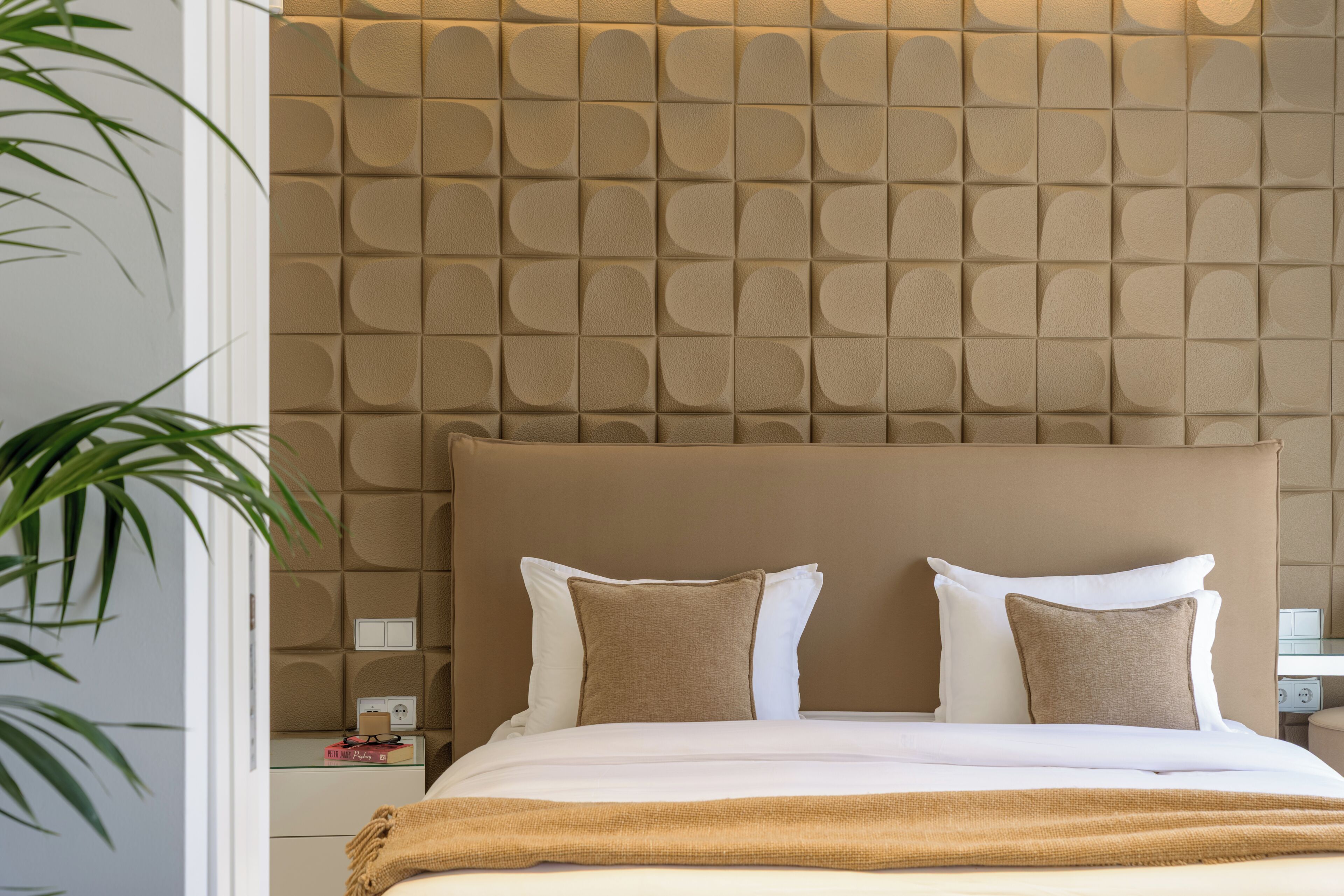 Une chambre d’hôtel avec un grand lit, une tête de lit à motifs et une table de chevet avec une lampe.