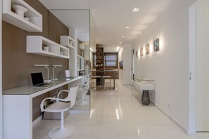 Una cocina moderna con muebles blancos, una mesa de comedor de vidrio y taburetes de bar.