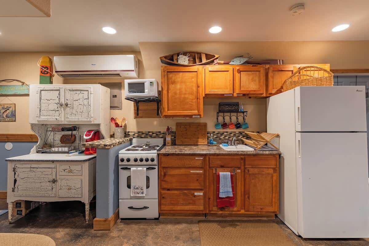 Een kleine keuken met houten kastjes, een witte koelkast, een fornuis en een magnetron.