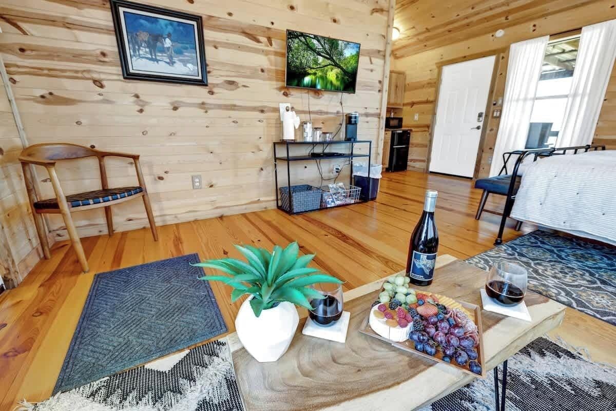 A wooden interior with a dining table, chairs, a TV, and a kitchen area.