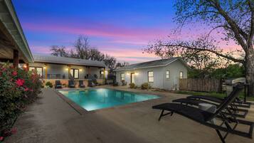 Relax by the pool surrounded by lush greenery and comfortable lounge chairs.