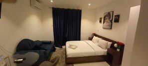 A hotel room with a bed, a desk, a chair, and a curtain. - Bizzi studio ad Legationis Hortos (Accra)