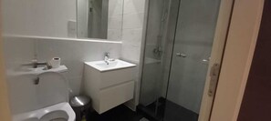 A bathroom with a toilet, sink, mirror, and shower. - Bizzi studio ad Legationis Hortos (Accra)