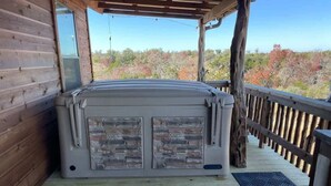 A hot tub on a wooden deck with a view of trees.