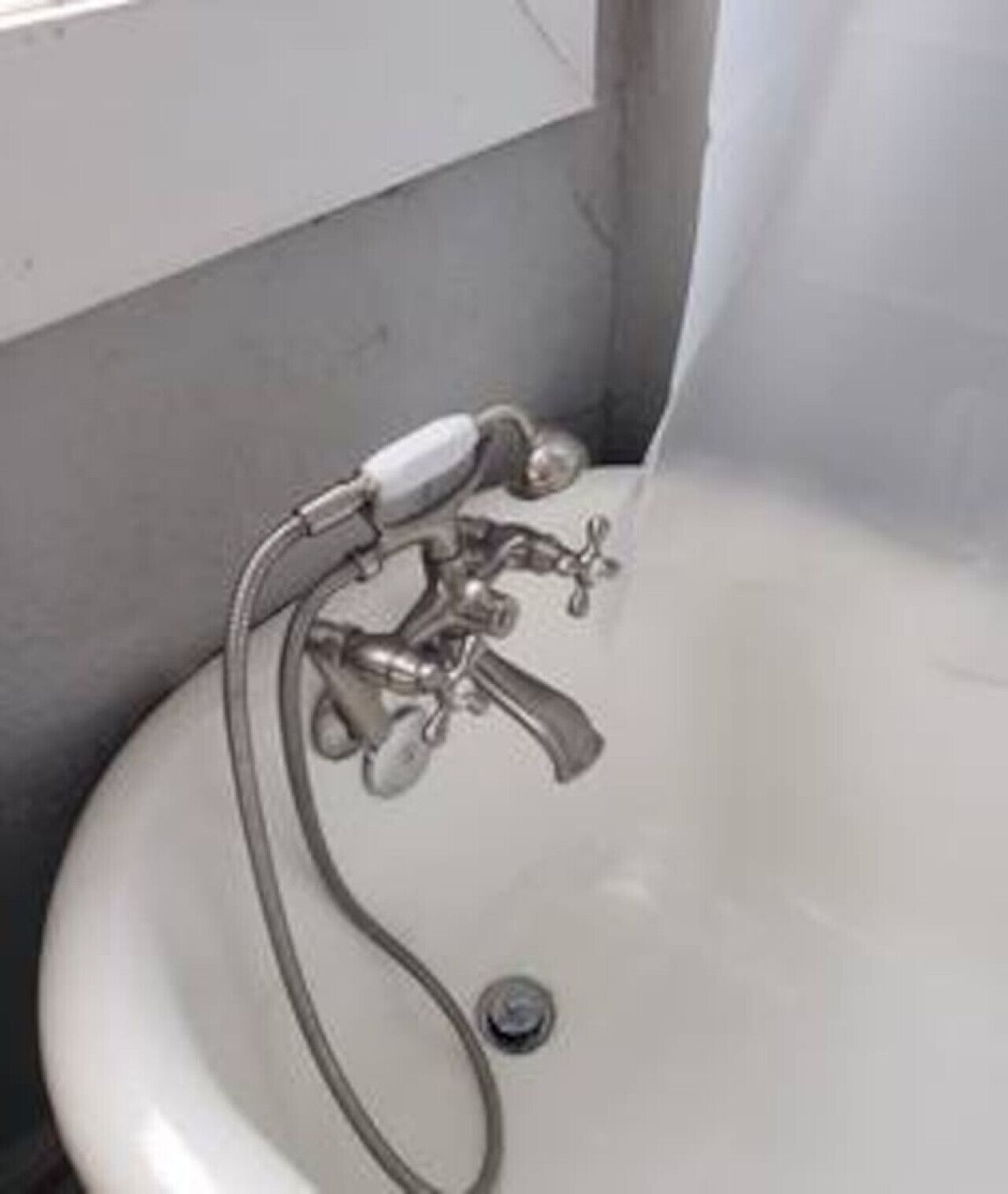 Un bagno con un lavandino bianco, un rubinetto e un soffione.