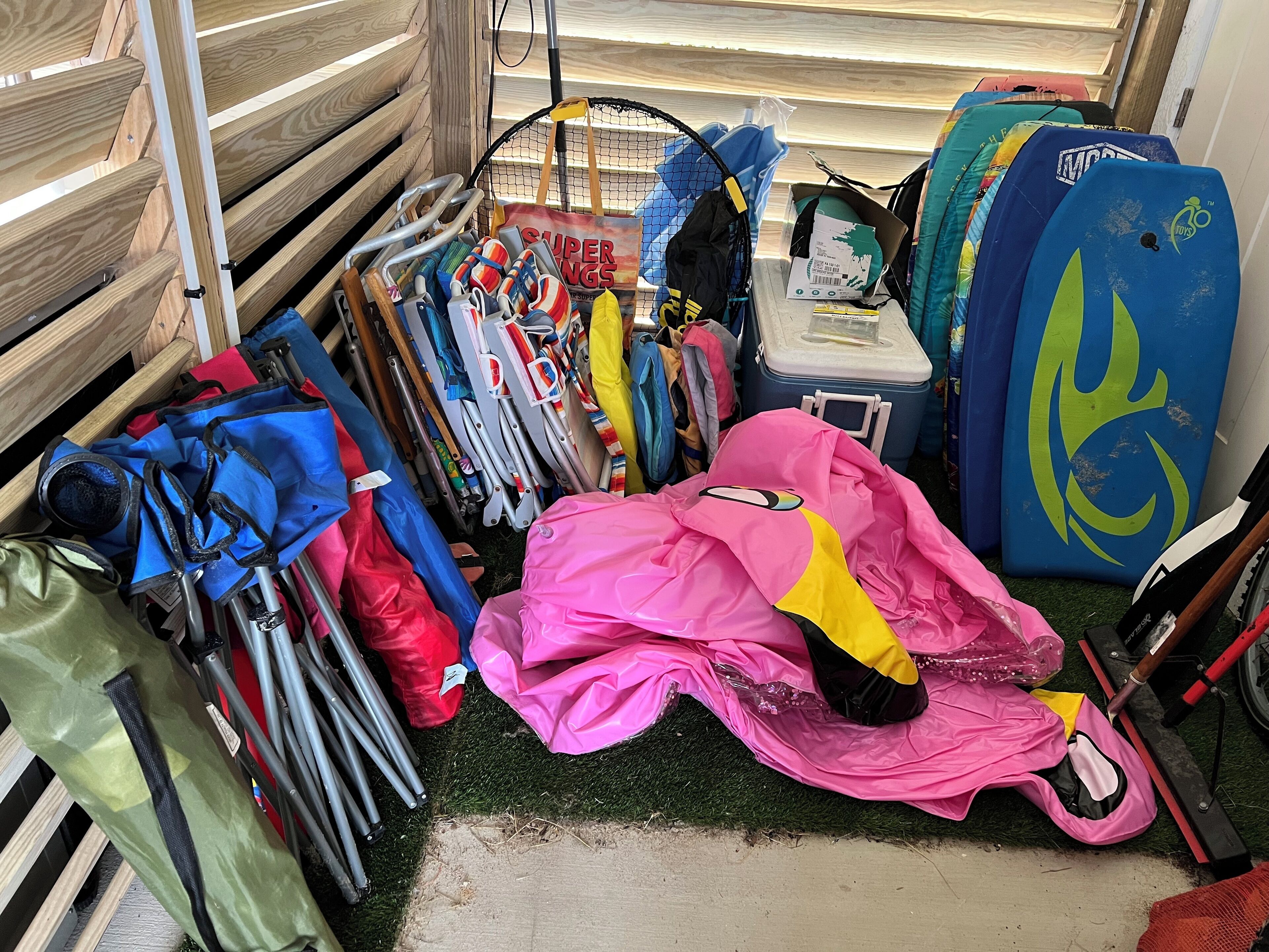 A storage area with various items including a bicycle, a cooler, and multiple bags and umbrellas.